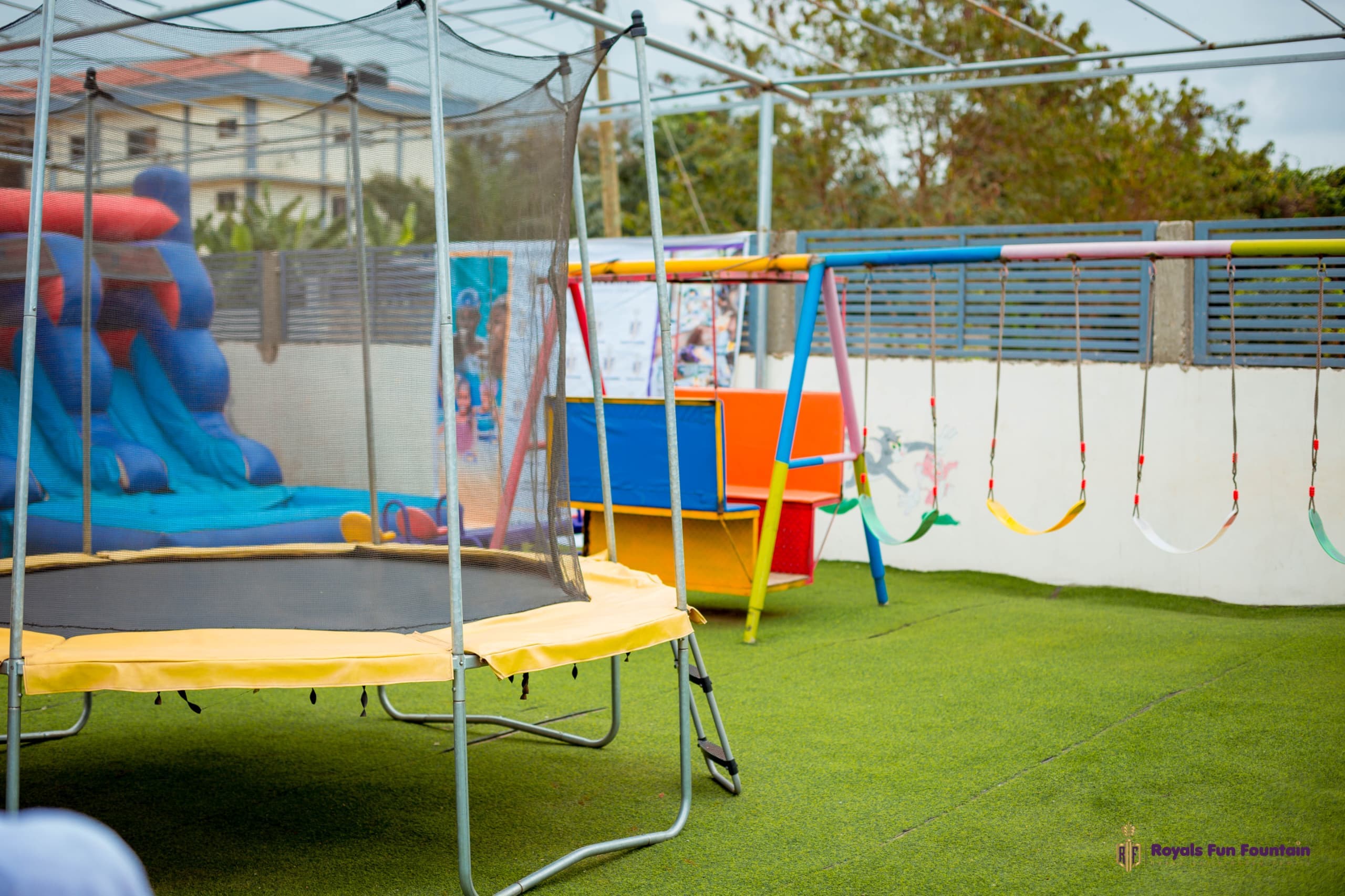 The playground with a trampoline, swings and bouncy castle on green turf