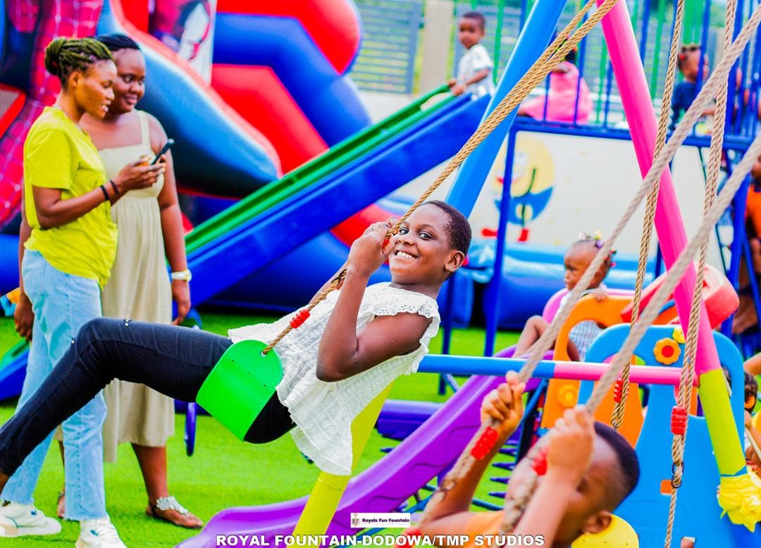 A girl laughing on a swing in front of the bouncy castle