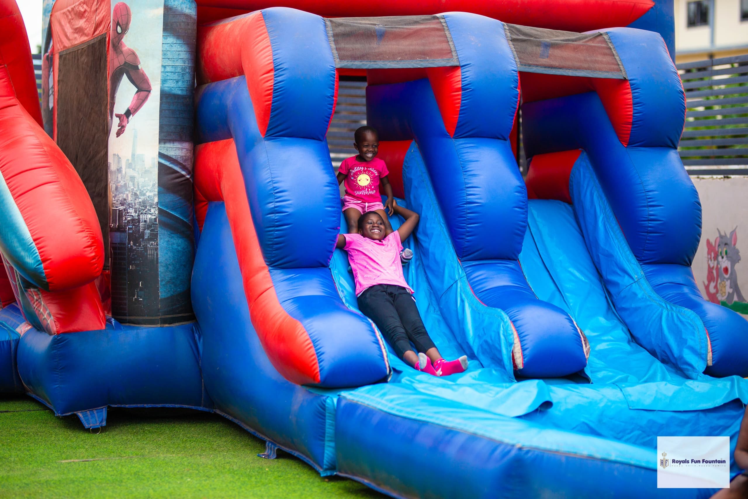 Two girls sliding down a red and blue bouncy castle