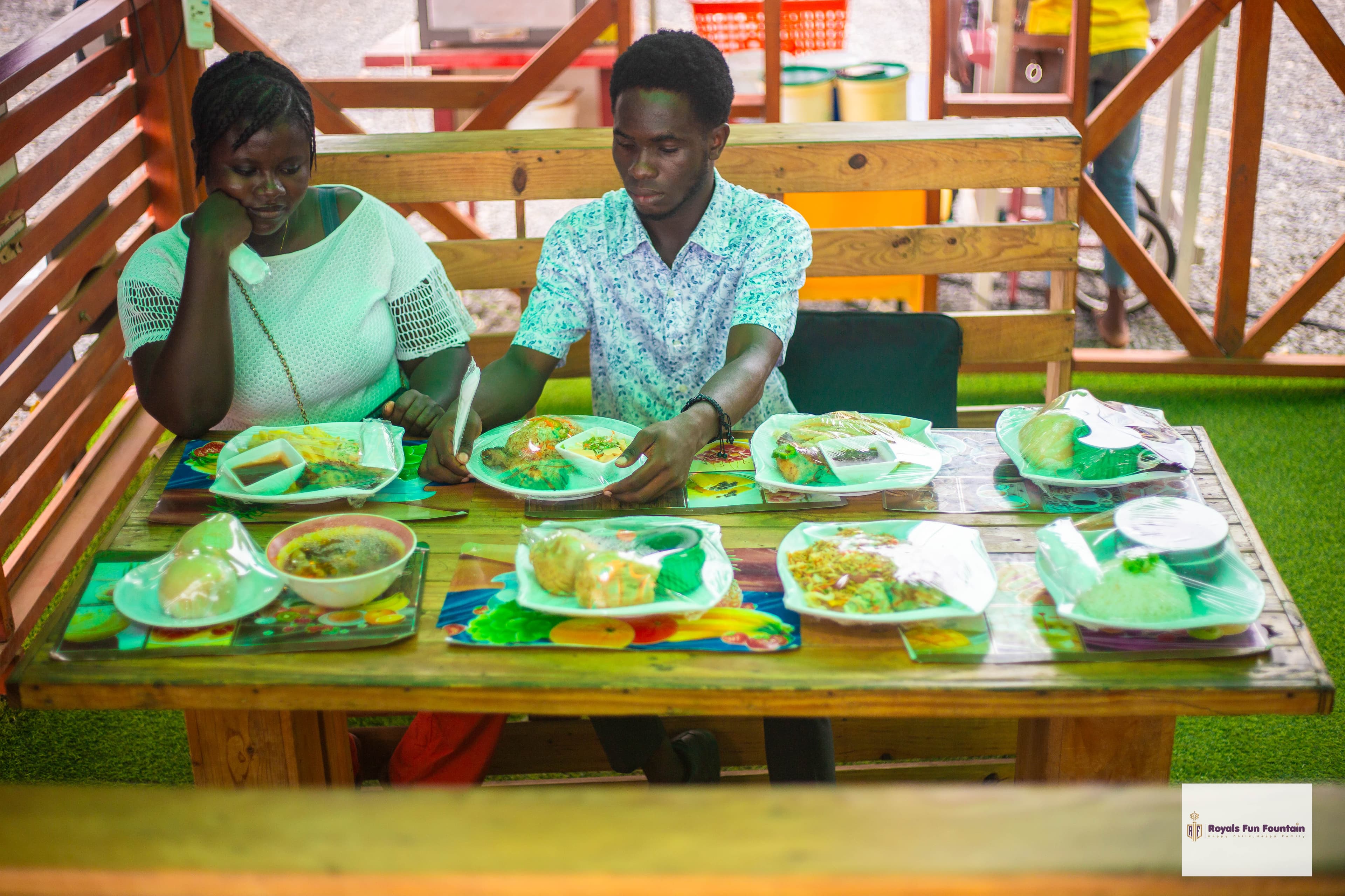 A couple at a wooden table laid with plates of food
