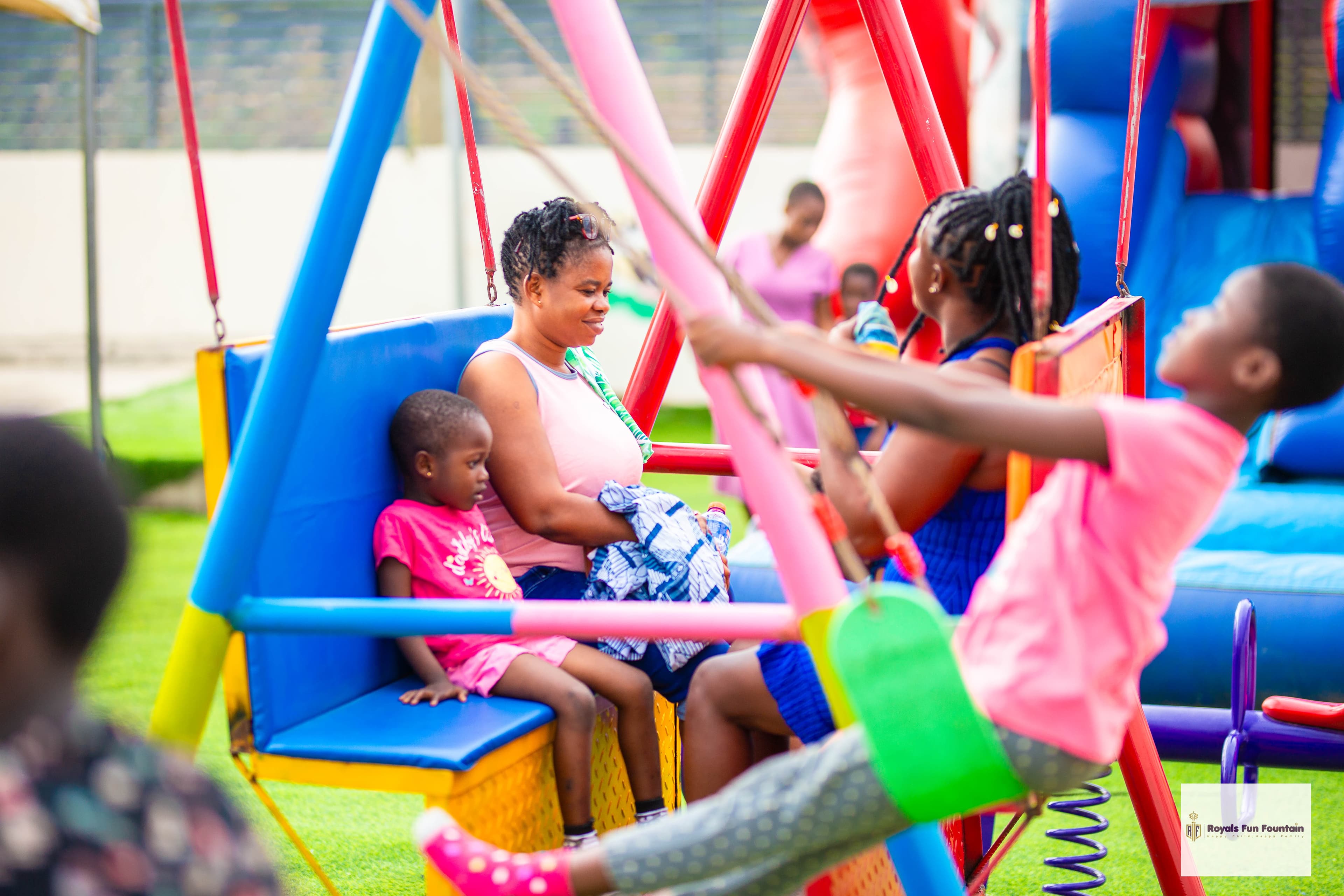 Children on the swings while a mother watches from a bench swing