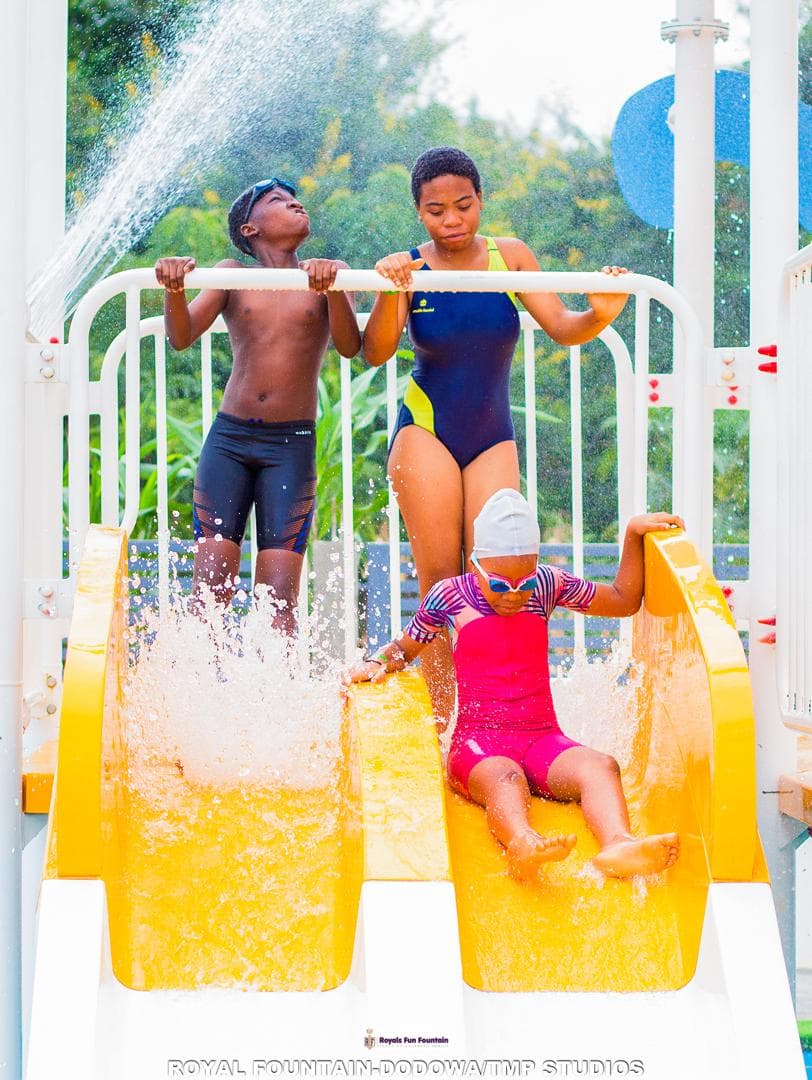 Kids racing down the twin yellow slides under a water spray